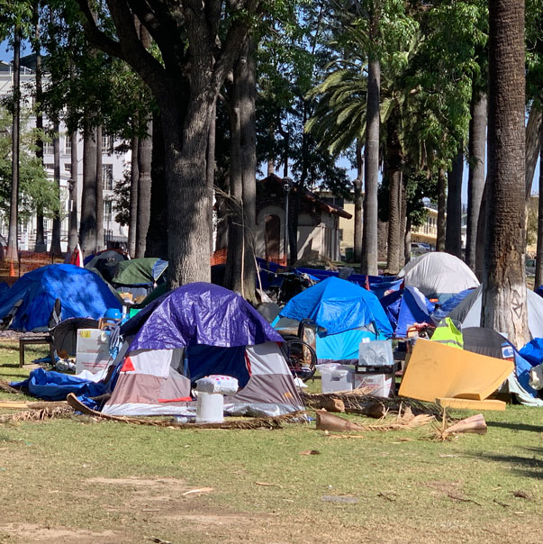 A image showing a number of homeless people tents in an open area
