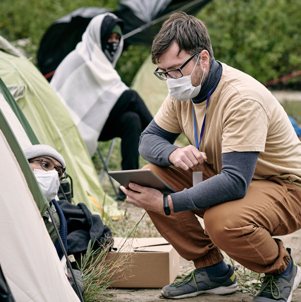 A volunteer talking to a refugee with an tablet in his hand